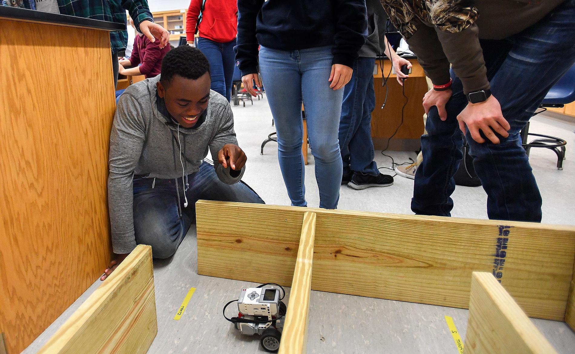 Students pilot a robot through a wooden maze