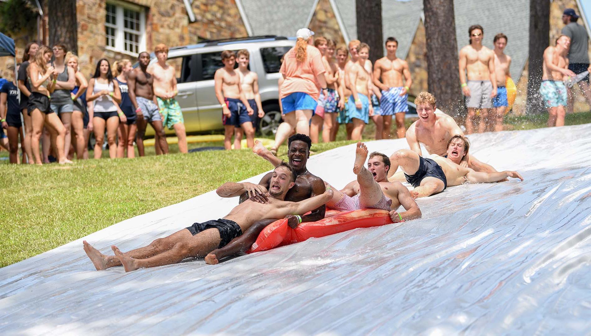 Group of guys laughing on a slip n slide