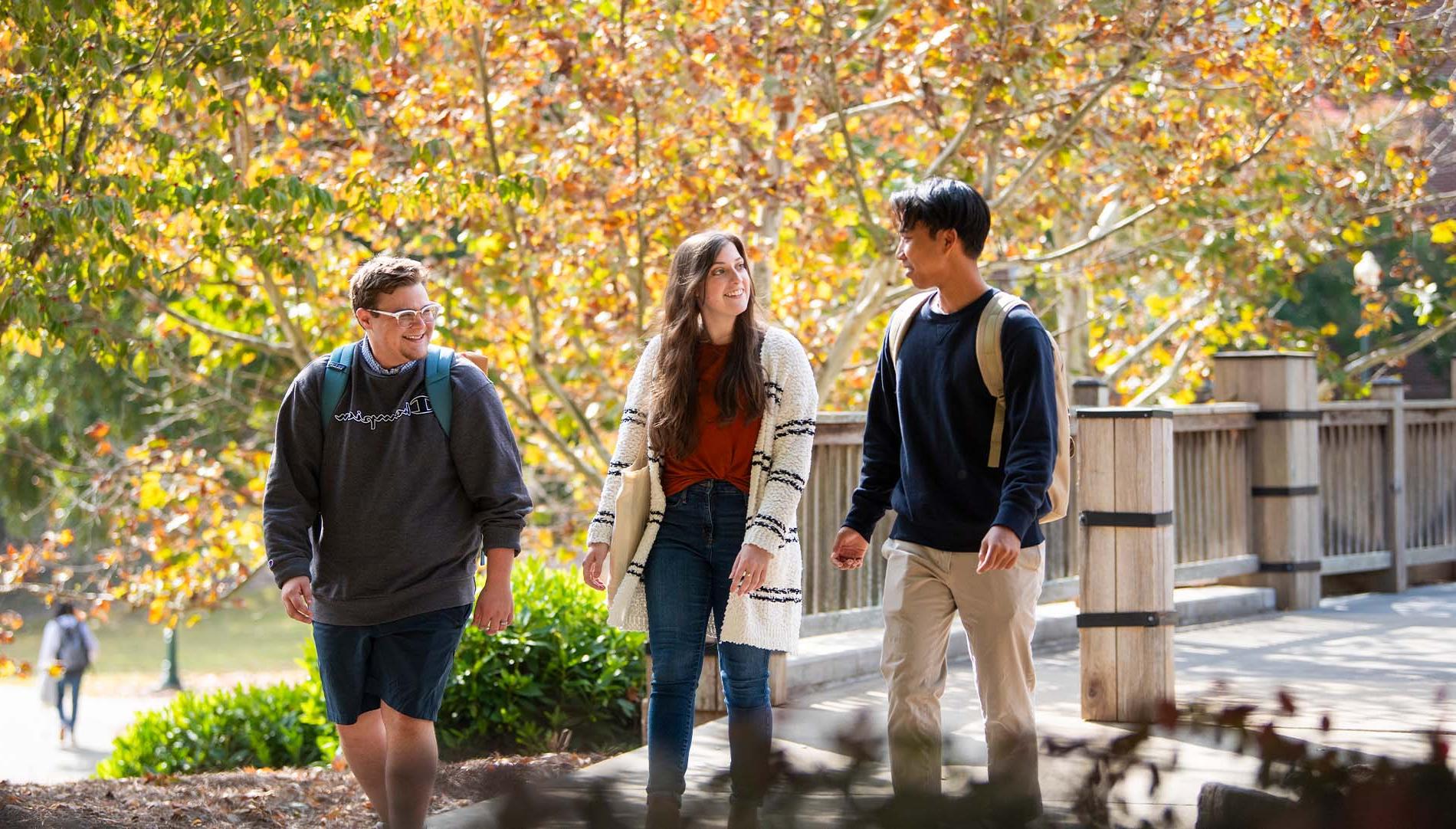 three students walking on campus during the fall